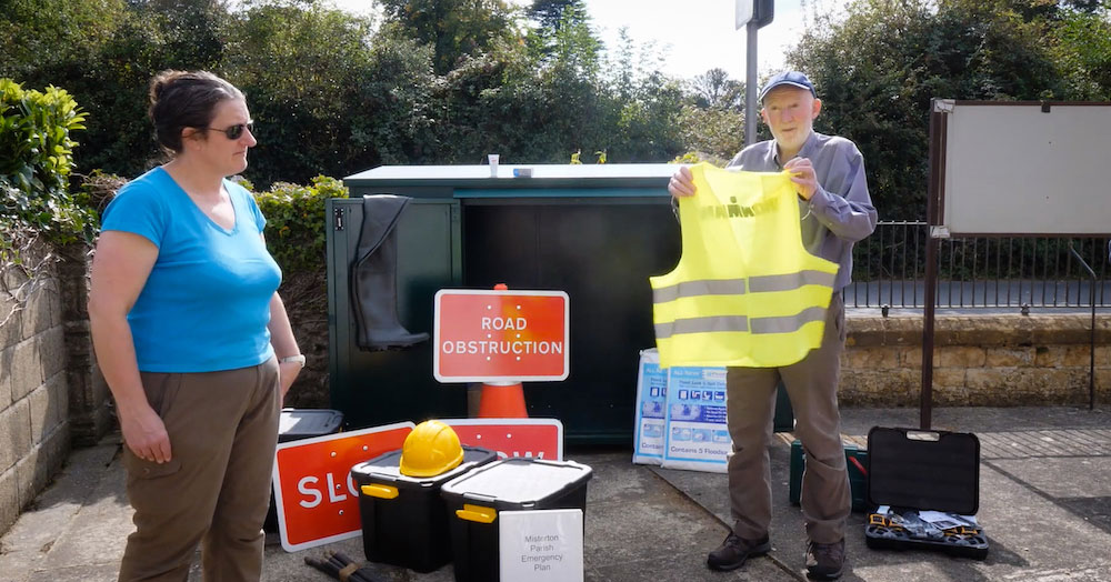 Sally Gray and Phil Clifton of Misterton Emergency and resilience Team with signs and equipment such as a hi-viz jacket help up by Mr Clifton.