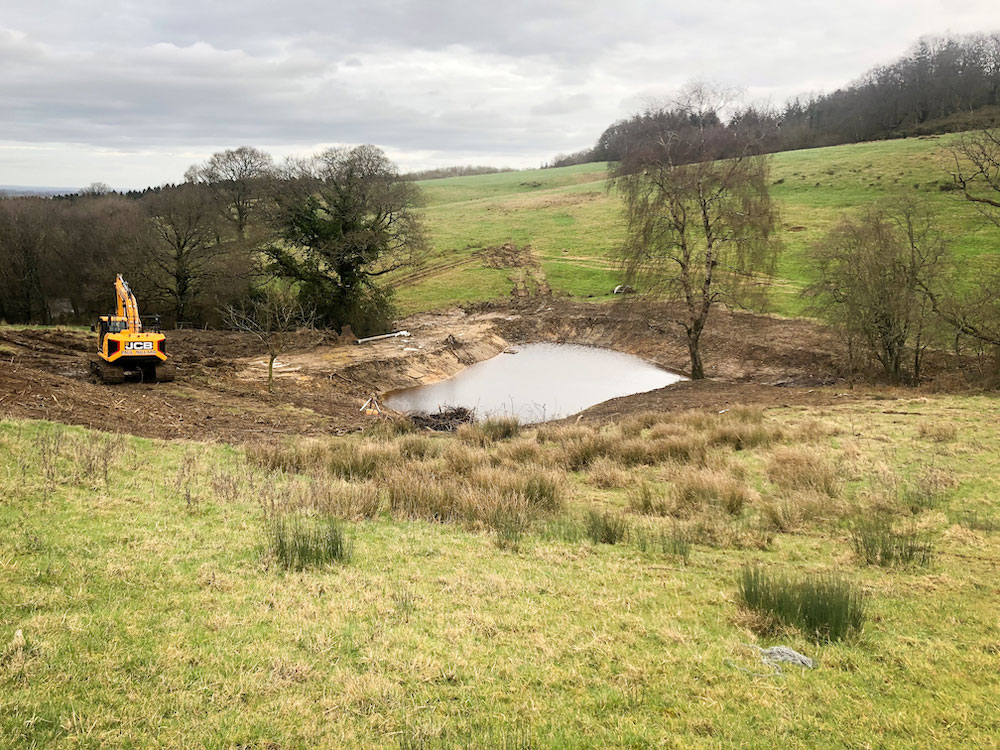 Water in newly created pond in low spot between wintry sloping hills.