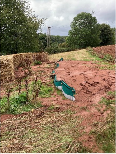 A tide of mud that has overtopped temporary filter fences, erected in front of a line of straw bales.